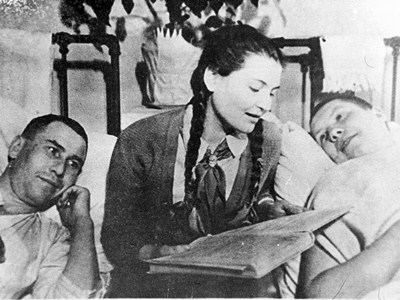 A Pioneer Girl in a Hospital room reading a book to the wounded. 1941-1945. The State Archive of Perm Krai